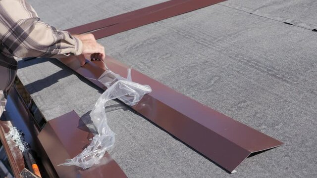 Preparation of metal roofing parts for installation. Removing the protective plastic film. Roofing works in a private house.