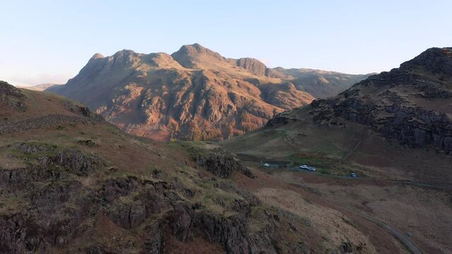 4k aerial drone footage showing beautiful view of Lake District mountains; The Langdale Pikes. Taken on a Spring morning with stunning golden light on the Cumbrian landscape.