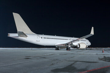 Fototapeta na wymiar Modern white passenger airplane on the night airport apron