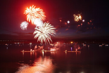 Holiday fireworks above water with reflection on the black sky background