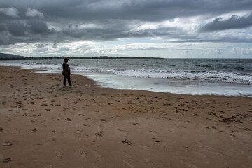 Woman standing on a beach, looking at the Atlantic Ocean