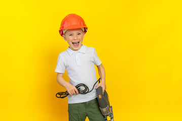 Little boy in a helmet with an electric tool on a yellow background, dressed in a white t-shirt