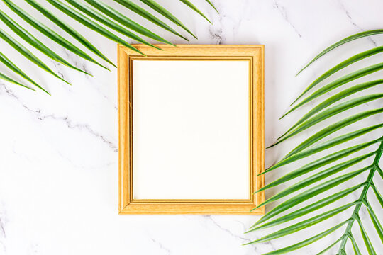 Top view of retro wooden empty photo frame with natural decorations, branches and leaves on light background as a mock up and blank template for cards, posters and paintings design.