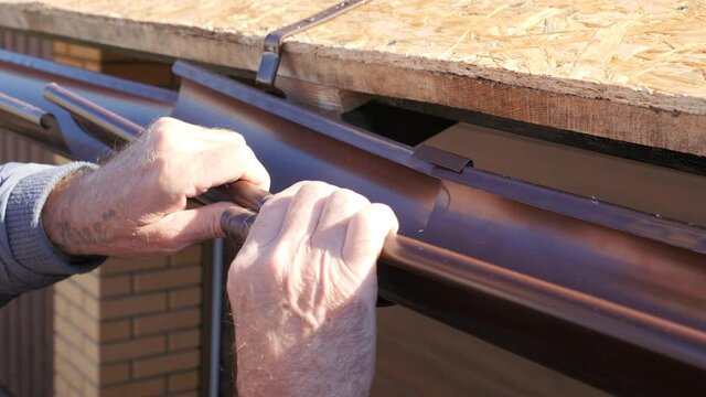 Installation of a gutter. Docking of the metal chute. Installation of a gutter. Roofing works in a private house.