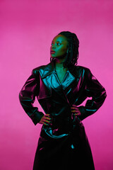 glamorous fashion portrait of african american girl in leather coat. neon pink light