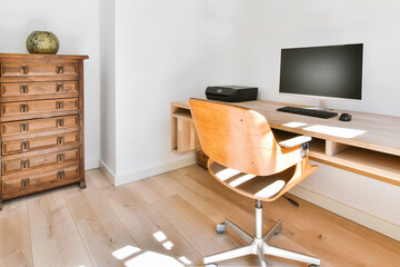 Modern interior of light study room with wooden wall mounted table and computer under shelves with...