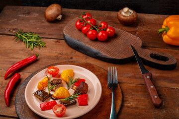 Antipasta on a plate on a wooden table next to vegetables on wooden boards.