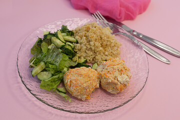 Salad, porridge and minced baked meat with a napkin on a plate on a pink background. Dietary nutrition.