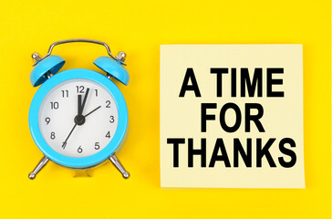 On a yellow background lie a clock and a sticker sheet with the inscription - A TIME FOR THANKS