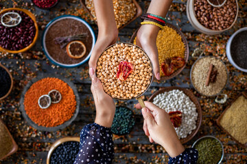Various of beans at the hands of two women in the bowl