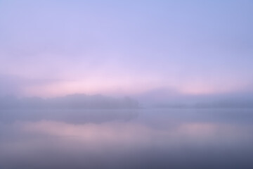 Fototapeta premium Landscape of the foggy, summer shoreline of Whitford Lake at dawn, Fort Custer State Park, Michigan, USA