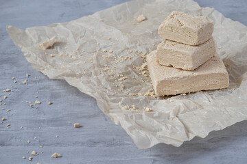 Peanut halva lying on parchment paper on a gray background. Traditional national dessert. Turkish, Arabic, Oriental cuisine. Close-up.	