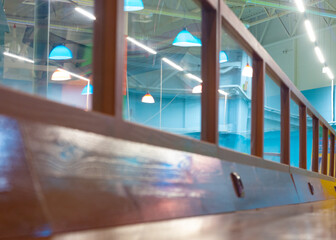 A wooden, long table with glass windows in a hangar with blue and white lamps. 