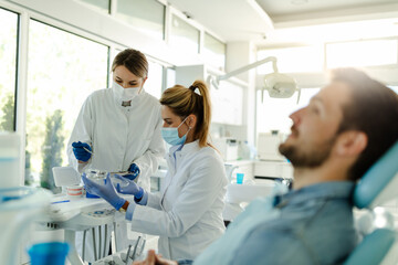 The female dentist and the assistant prepare the instruments for the dental examination.