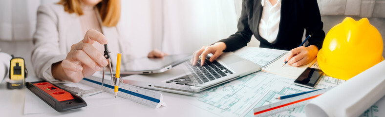 Engineers or architects is watching on model building and blueprint in working site.Construction...