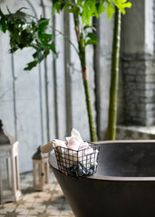 Moroccan style bathtub with green flowers and natural cosmetics. Gray bathroom interior