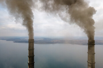 Aerial view of coal power plant high pipes with black smoke moving up polluting atmosphere.