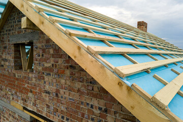 Obraz premium Aerial view of a brick house with wooden roof frame under construction.