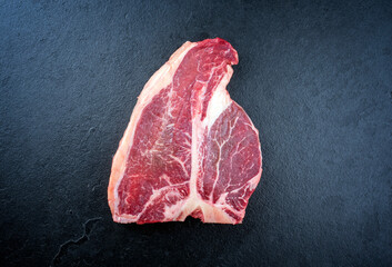 Raw dry aged wagyu porterhouse beef steak offered as top view on black background with copy space