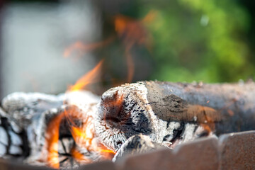 Close up of brightly burning wooden logs with yellow hot flames of fire.