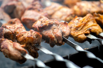 Shashlik or shish kebab preparing on barbecue grill over hot charcoal. Grilled pieces of pork meat on metal skewers.