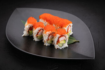 Japanese cuisine. Rolls on a black plate on a wooden table
