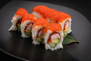 Japanese cuisine. Rolls on a black plate on a wooden table
