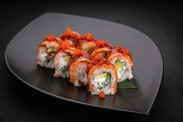 Japanese cuisine. Rolls on a black plate on a wooden table
