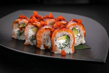 Japanese cuisine. Rolls on a black plate on a wooden table
