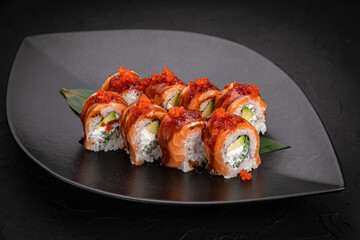 Japanese cuisine. Rolls on a black plate on a wooden table
