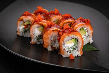 Japanese cuisine. Rolls on a black plate on a wooden table
