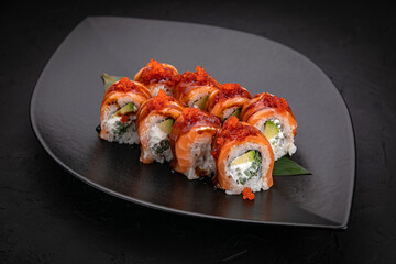 Japanese cuisine. Rolls on a black plate on a wooden table