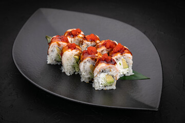 Japanese cuisine. Rolls on a black plate on a wooden table
