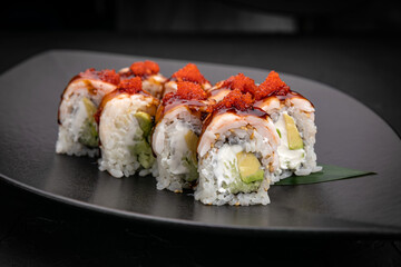 Japanese cuisine. Rolls on a black plate on a wooden table
