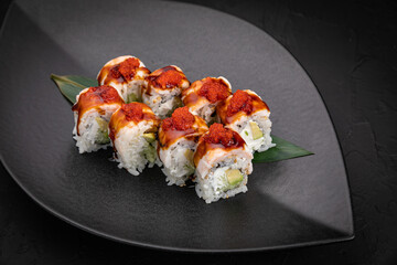 Japanese cuisine. Rolls on a black plate on a wooden table
