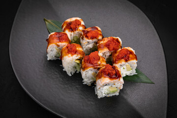Japanese cuisine. Rolls on a black plate on a wooden table
