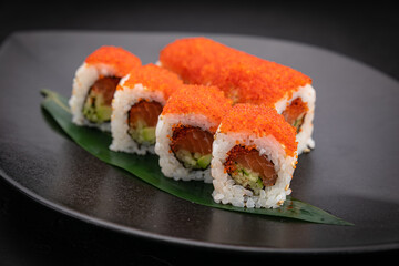Japanese cuisine. Rolls on a black plate on a wooden table
