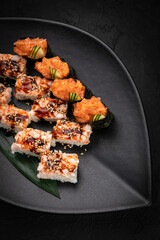 Japanese cuisine. Rolls on a black plate on a wooden table
