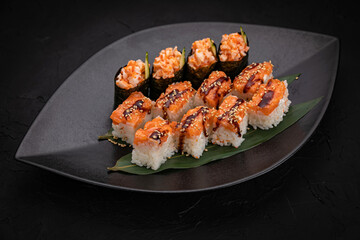 Japanese cuisine. Rolls on a black plate on a wooden table