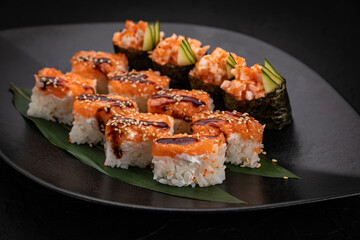 Japanese cuisine. Rolls on a black plate on a wooden table