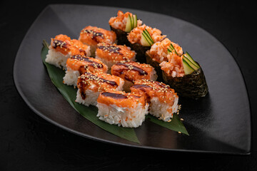 Japanese cuisine. Rolls on a black plate on a wooden table