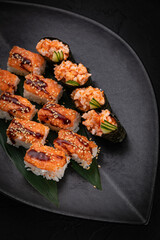 Japanese cuisine. Rolls on a black plate on a wooden table