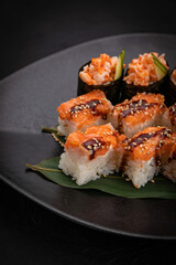 Japanese cuisine. Rolls on a black plate on a wooden table