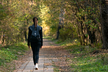 Lonely girl is walking along the alley of the park. Back view. Alone with myself