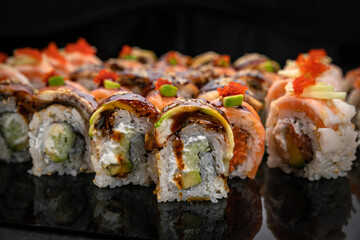 Japanese cuisine. Rolls on a black plate on a wooden table