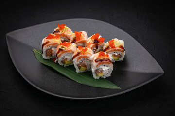 Japanese cuisine. Rolls on a black plate on a wooden table