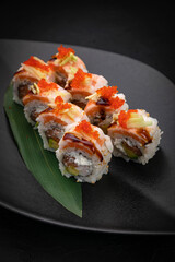Japanese cuisine. Rolls on a black plate on a wooden table