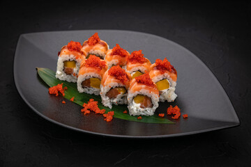 Japanese cuisine. Rolls on a black plate on a wooden table