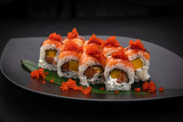 Japanese cuisine. Rolls on a black plate on a wooden table