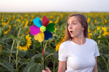 Girl looks in surprise at windmill toy in shape of flower. Green energy concept